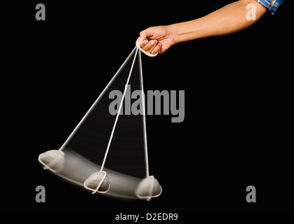 Close-up of a person's hand balancer un pendule en pierre Banque D'Images