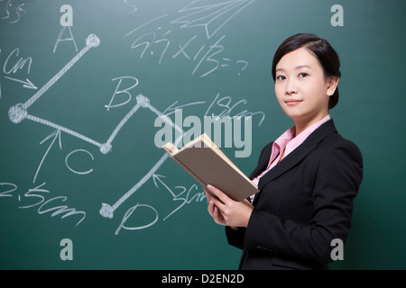 Femme sérieuse teacher holding manuels scolaires en classe Banque D'Images