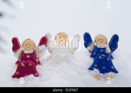 Trois anges en bois décorative dans la neige. Banque D'Images