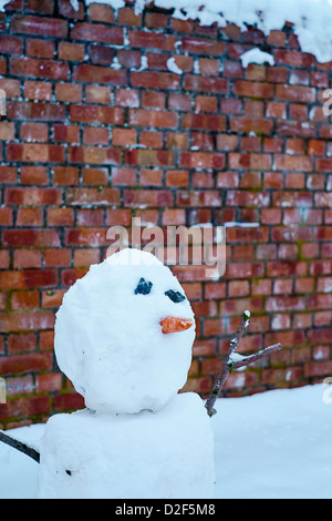 Le SNOWMAN contrastant contre un mur de briques Banque D'Images