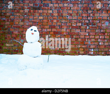 Le SNOWMAN contrastant contre un mur de briques Banque D'Images