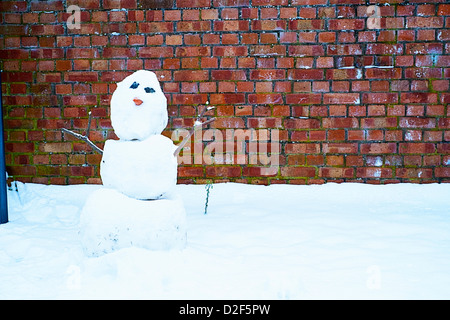 Le SNOWMAN contrastant contre un mur de briques Banque D'Images