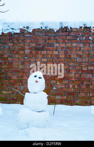 Le SNOWMAN contrastant contre un mur de briques Banque D'Images