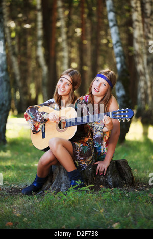 Filles Hippie avec guitare assis sur la souche Banque D'Images