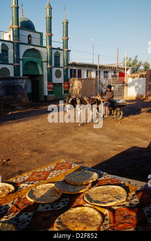 Pain à vendre dans une rue de Shanghai, la province du Xinjiang, en Chine. Un homme passe par Uygur sur un chariot tiré par un âne. Banque D'Images