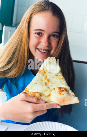 Teenage girl eating Tranche de pizza, gros plan, smiling, Miami Banque D'Images