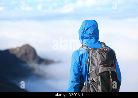 Vue arrière du jeune homme alpiniste enjoying view lors du sommet en haut alpine wear avec sac à dos dans les montagnes de haute altitude Banque D'Images