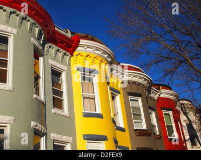 Une ligne de couleurs vives, dans rowhomes vintage gris, rouge, jaune, blanc, et marron, contre un brillant ciel bleu, dans l'hiver. Banque D'Images