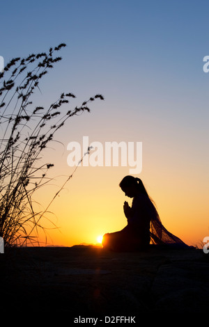 Indian woman praying au coucher du soleil dans la campagne indienne. Silhouette Banque D'Images