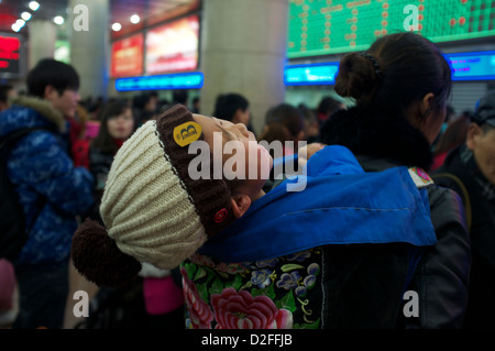 Un bébé pleure pendant que sa mère queue pour acheter des billets de train à la gare de Pékin, Chine. 22-Jan-2013 Banque D'Images