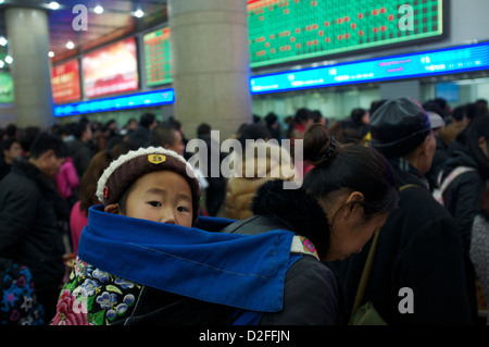 Une mère chinoise tenant un bébé sur son dos queue pour acheter des billets de train à la gare de Pékin, Chine. 22-Jan-2013 Banque D'Images