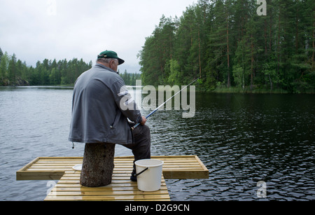 Un homme âgé d'une pêche à la jetée en bois , Finlande Banque D'Images