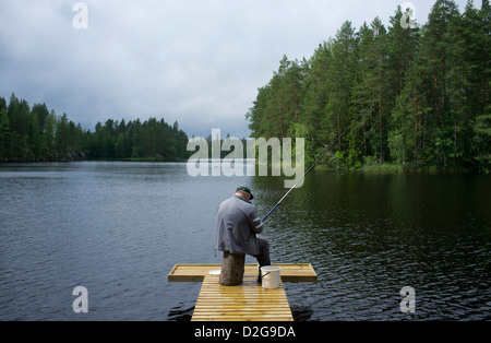 Un homme âgé d'une pêche à la jetée en bois , Finlande Banque D'Images