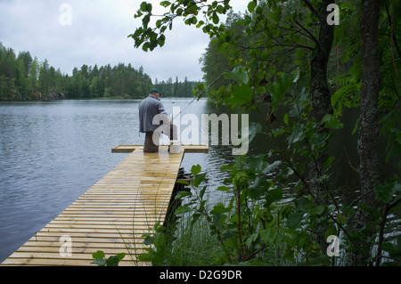 Un homme âgé d'une pêche à la jetée en bois , Finlande Banque D'Images