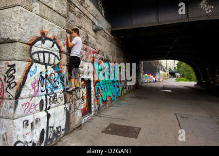 Un grimpeur pratique ses techniques sur un mur le long de la rivière Danube à Vienne, Autriche Banque D'Images