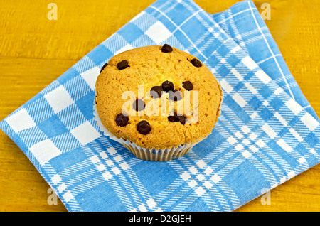 Un petit gâteau au chocolat sur une serviette à carreaux bleu contre une planche en bois Banque D'Images