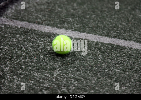 C'est une photo d'une balle de tennis qui est dans une couleur jaune. C'est sur le terrain d'un court de tennis en ligne près de texture synthétique Banque D'Images