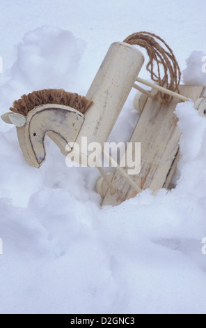 Jouet en bois cheval de modèle sur l'empattement peint en blanc et souligné par chaîne crinière et la queue s'est effondré dans la neige molle Banque D'Images