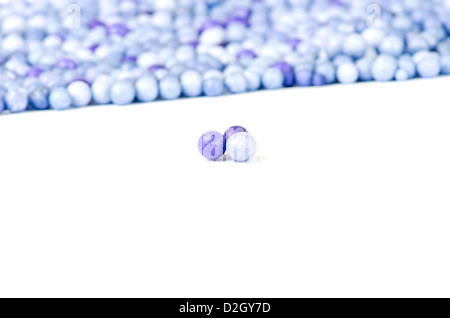 L'une bleue et deux petites perles violet isolé sur fond d'autres perles. Banque D'Images