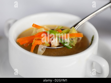 Soupe au poulet avec légumes en cuillère et plaque profonde blanc Banque D'Images