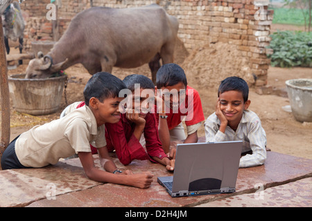 L'Inde, Uttar Pradesh, quatre enfants village looking at laptop computer Banque D'Images