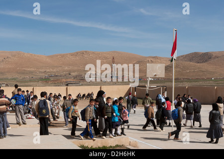 Les élèves de primaire et des jeux pour enfants à l'extérieur de l'école kurde irakienne dans le Nord de l'Iraq avec l'exploration pétrolière Rig derrière Banque D'Images