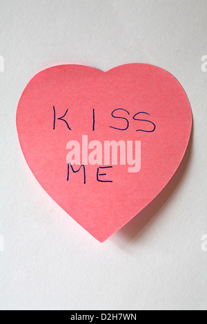 Kiss me message écrit sur en forme de coeur rose post-it-notes isolé sur fond blanc Banque D'Images