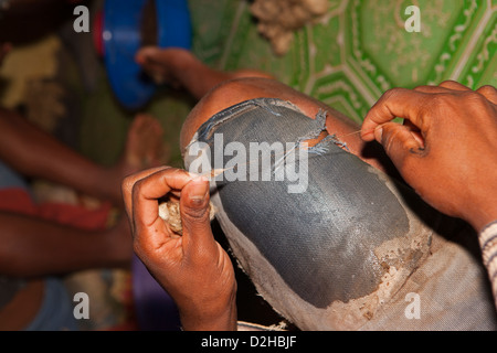 Madagascar, Ambalavao, Soalandy Atelier de soie, des mains de travailleur de tourner la soie brute sur la cuisse Banque D'Images