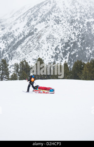 Ski alpin de sauvetage dans les Pyrénées d'Andorre. Un skieur blessé retourne au centre médical par une patrouille de neige médic attaché dans un traîneau. Banque D'Images