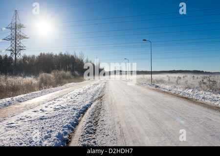 Soleil sur les lignes de transport d'énergie électrique à proximité en hiver contre le ciel bleu avec du brouillard Banque D'Images