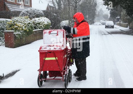 Facteur distribue le courrier à Londres en janvier une chute de neige. Banque D'Images