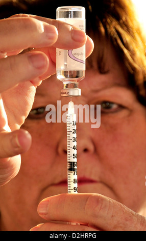 A senior patient prépare une seringue qu'elle utilisera pour s'injecter de l'insuline à son abdomen pour le traitement du diabète de type 2. Banque D'Images