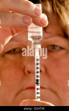 A senior patient prépare une seringue qu'elle utilisera pour s'injecter de l'insuline à son abdomen pour le traitement du diabète de type 2. Banque D'Images