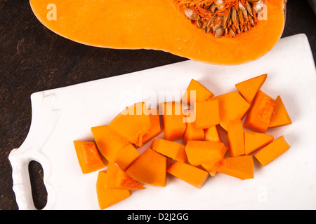 La moitié orange citrouille fraîche avec morceaux de coupe à bord Banque D'Images