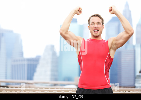 Jeune couple fit célébrer la flexion et montrant les muscles forts à l'extérieur avec New York City Skyline in background Banque D'Images