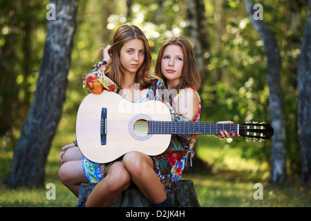 Filles Hippie avec guitare assis sur la souche Banque D'Images