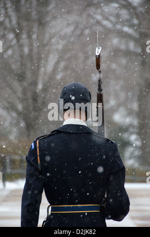 Un soldat monte la garde dans la neige qui tombe sur le tombeau de l'inconnu au cimetière national d'Arlington dans la neige. Le garde s'engage dans un jeu de routine dans laquelle il marches 21 marches à descendre le mat noir derrière le tombeau, tourne, fait face à l'est pour 21 secondes, se retourne et fait face au nord pendant 21 secondes, puis prend 21 pas en bas de la mat et répète le processus. Banque D'Images