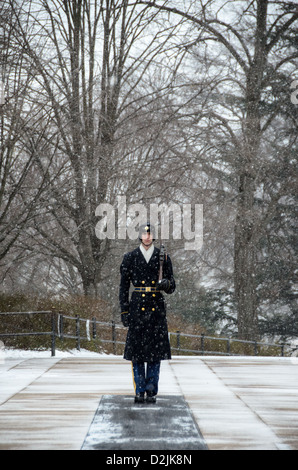 Un soldat monte la garde dans la neige qui tombe sur le tombeau de l'inconnu au cimetière national d'Arlington dans la neige. Le garde s'engage dans un jeu de routine dans laquelle il marches 21 marches à descendre le mat noir derrière le tombeau, tourne, fait face à l'est pour 21 secondes, se retourne et fait face au nord pendant 21 secondes, puis prend 21 pas en bas de la mat et répète le processus. Banque D'Images