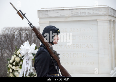Tombeau du soldat inconnu Sentinelle Arlington Virginie / ARLINGTON, Virginie - Une sentinelle du 3rd U.S. Infantry Regiment (« la vieille garde ») monte la garde au tombeau des inconnus au cimetière national d'Arlington pendant les chutes de neige. La vieille Garde a assumé la tutelle permanente du tombeau le 6 avril 1948, en maintenant une surveillance ininterrompue de 24 heures qui a commencé le 1er juillet 1937. La sentinelle suit une routine précise — faire 21 pas le long du tapis noir avant le sarcophage, puis s’arrêter 21 secondes face à l’est et 21 secondes face au nord — une cadence qui fait écho au salut des 21 canons, le plus haut militaire Banque D'Images