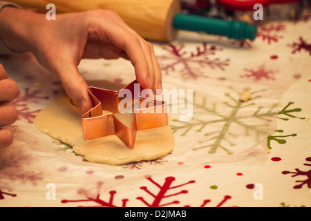 Une petite fille décore les biscuits de Noël avant de cuire eux Banque D'Images