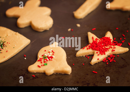 Une petite fille décore les biscuits de Noël avant de cuire eux Banque D'Images