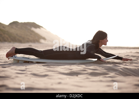 Femme pratiquant surfer sur la terre ferme avant d'entrer dans l'eau Banque D'Images