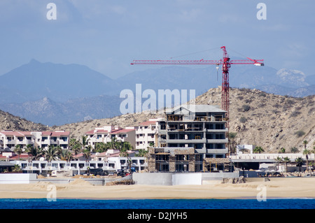 Grue de construction travaillant sur les condominiums et les hôtels pour les touristes sur la plage à Cabo San Lucas Mexique Banque D'Images