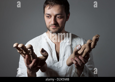 Jeune homme barbu tenant deux immenses mains simulée sur fond sombre Banque D'Images