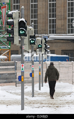 Leipzig, Allemagne, un homme avec un chapeau dans la neige va en vert sur un feu de circulation Banque D'Images