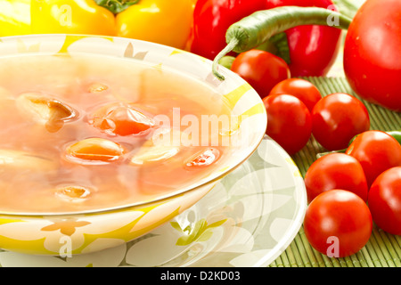 Soupe de tomate sur un fond de tomates et piments frais Banque D'Images