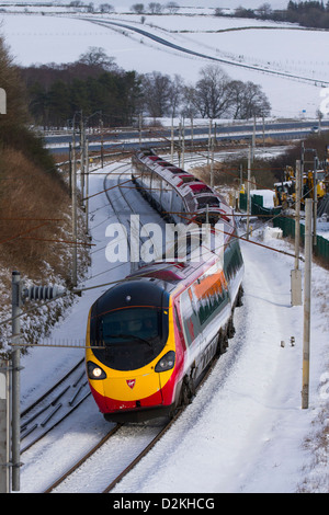 Voies, trains et passagers sur les passagers de Virgin Pendolino, train à grande vitesse à Beckfoot, Cumbria en conditions hivernales avec piste enneigée. ROYAUME-UNI Banque D'Images