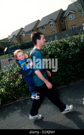 Les déficients visuels homme portant son jeune fils en porte-bébé, Biggleswade, Bedfordshire, Royaume-Uni. Banque D'Images