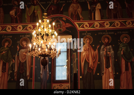 Saints peints sur un mur éclairé par un lustre dans une église orthodoxe à Bucarest, Roumanie Banque D'Images