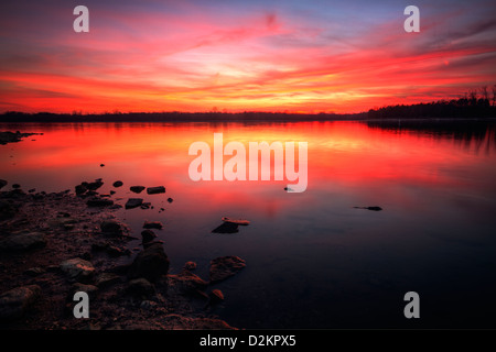 Un beau coucher du soleil illumine le ciel au-dessus d'un lac Banque D'Images